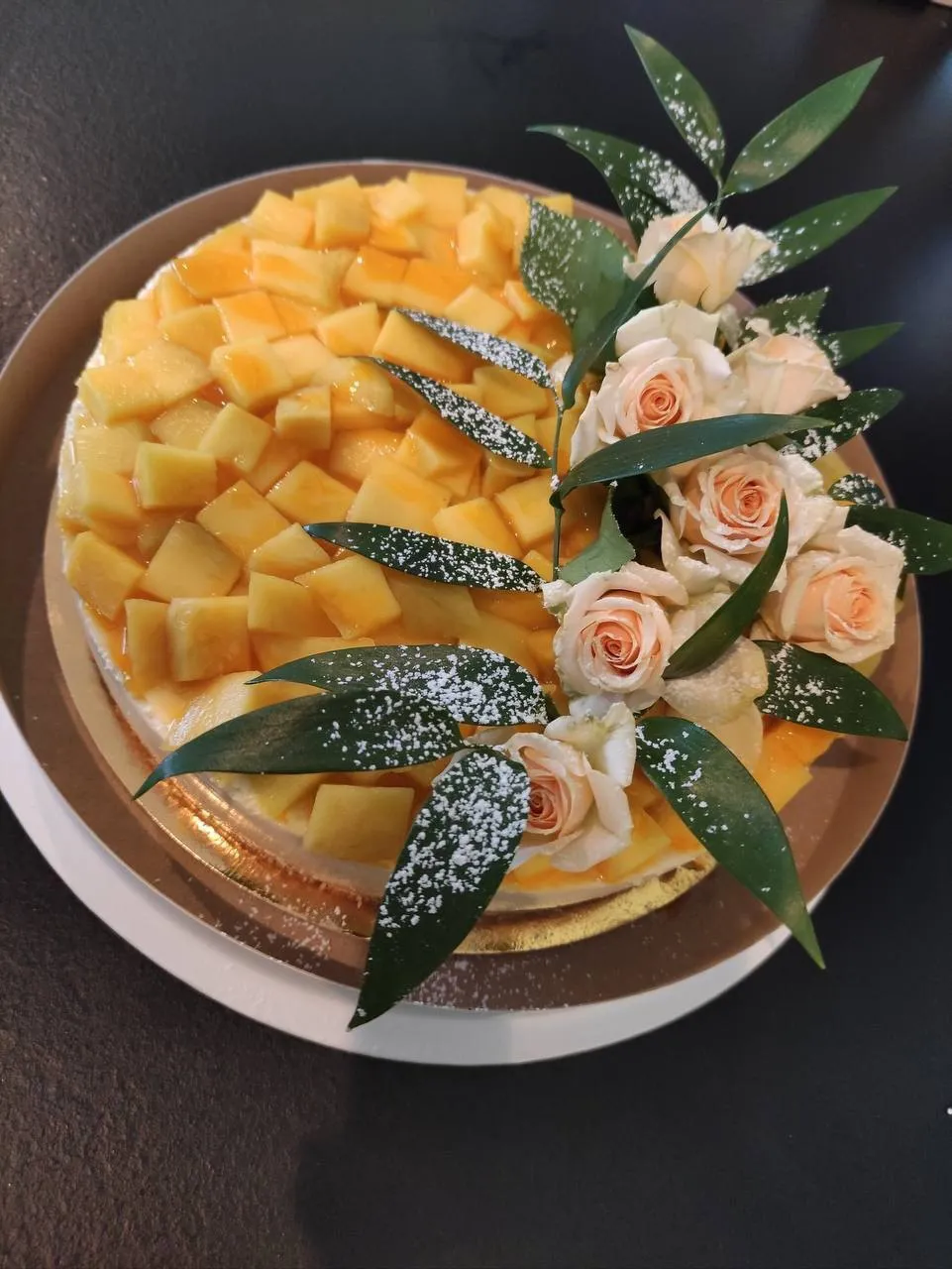 Mango torte, rotāta ar maigām persiku krāsas rozēm un zaļām lapām